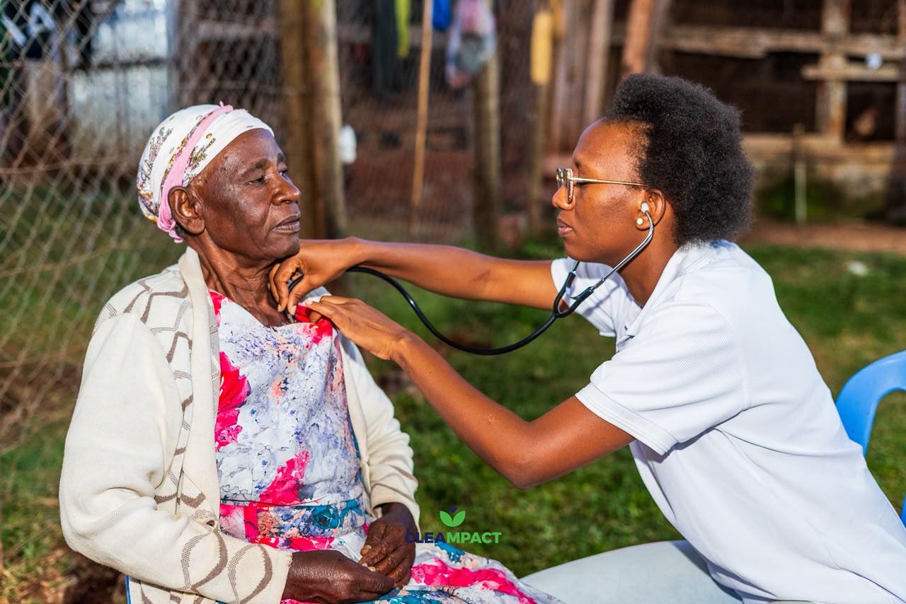 A mother holds her baby steady while two community health workers treat the child at a rural health post.